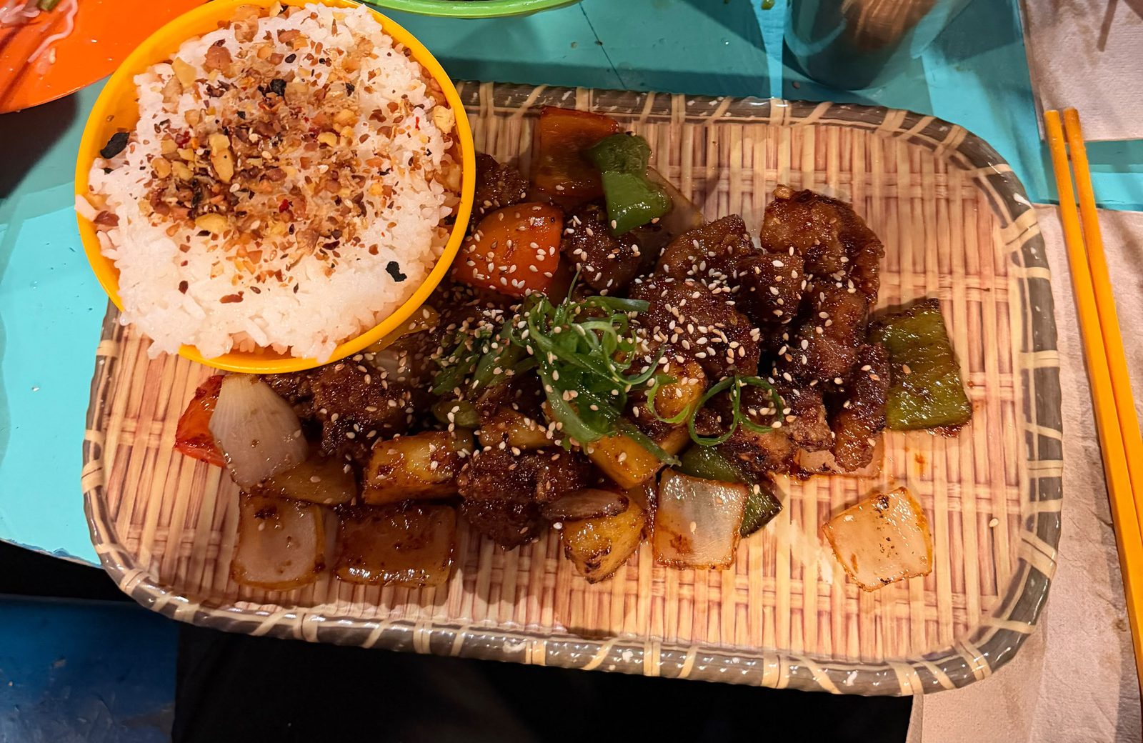 Pad Prew Wan Moo de Cang Tin: cerdo frito agridulce con ananá y morrones sobre una bandeja de mimbre, con un bol de arroz